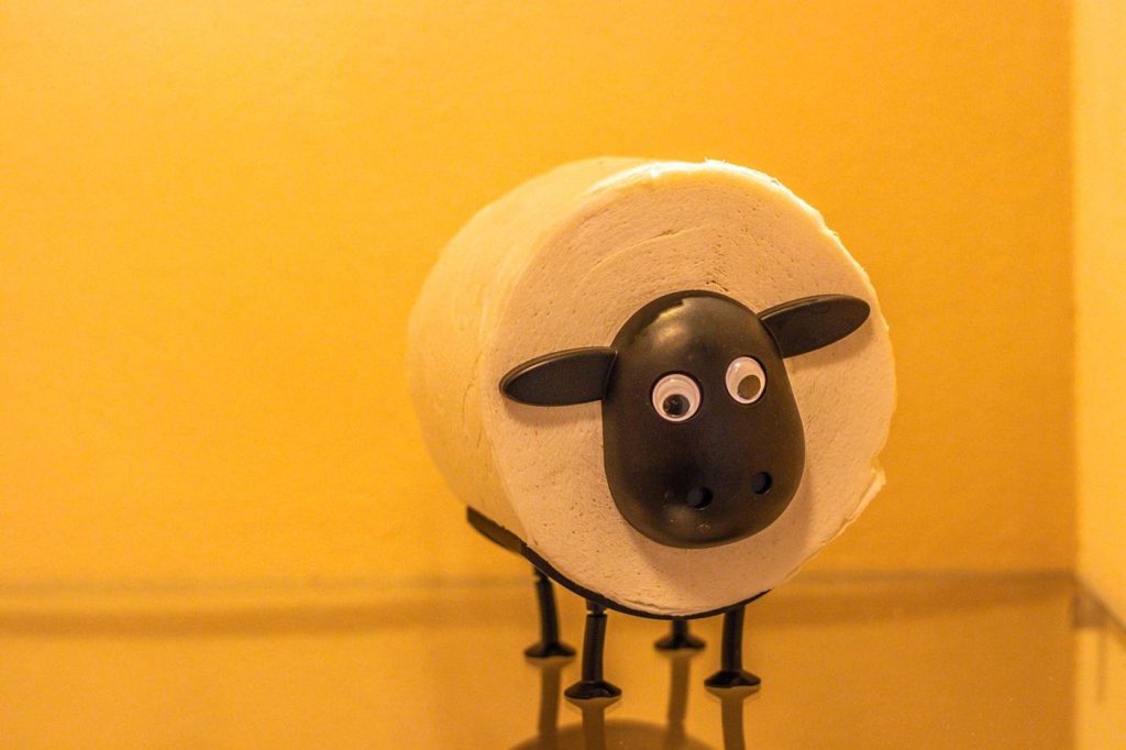 Toiletrolhouder in de vorm van een schaap tegen een okergele wand