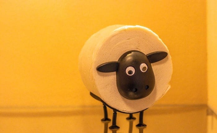 Toiletrolhouder in de vorm van een schaap tegen een okergele wand