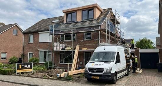 Woning met nieuwe dakkapel in aanbouw, steiger en bus van TISACO Bouwen