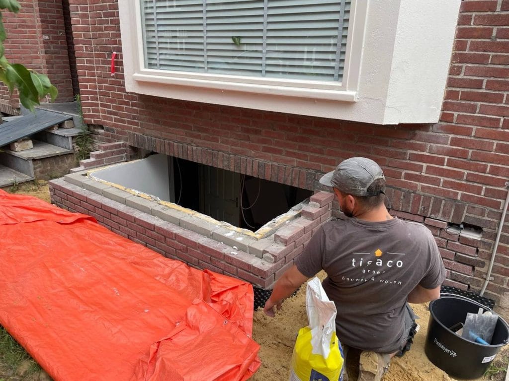 Vakman van TISACO herstelt metselwerk bij een kelderingang van een woning