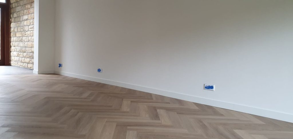 PVC visgraatvloer langs witte wand met natuursteen