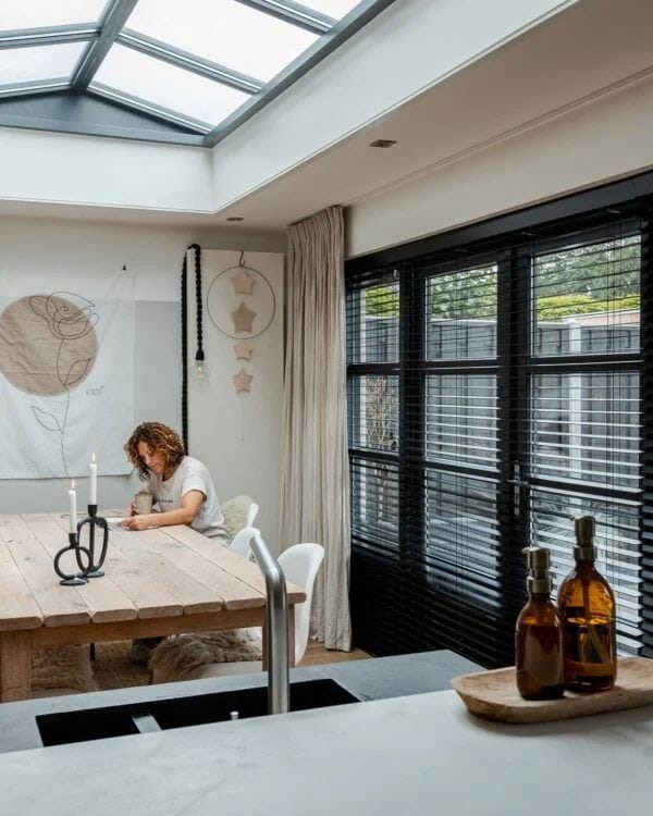 Keuken met zwarte shutters voor de grote ramen onder een lichtstraat