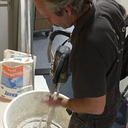 Vakman maakt stucmortel aan voor het herstellen van een wand