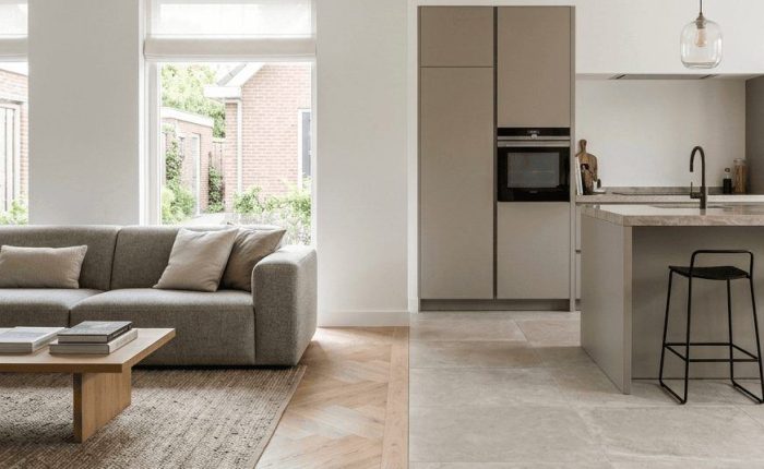 Open woonkeuken met een visgraatvloer in lichte eik naast een tegelvloer