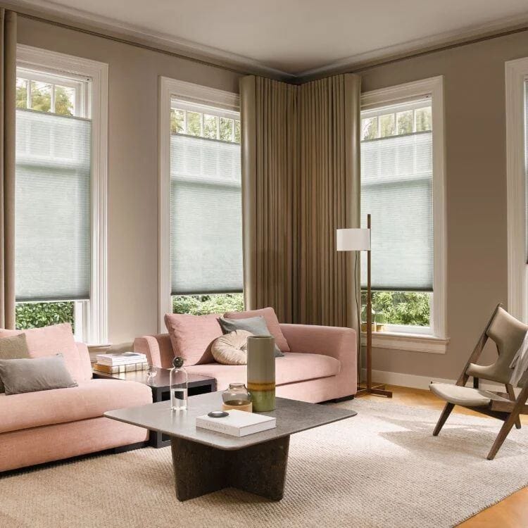 Woonkamer met warme verfkleur op de wanden, hoge ramen en een licht karpet